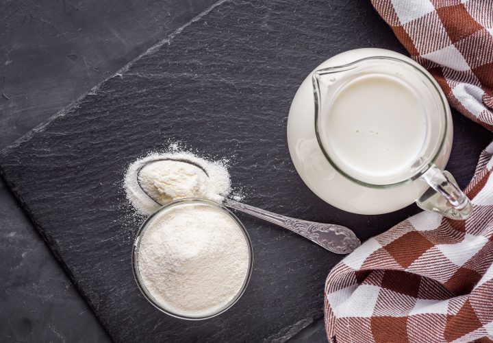 Un pichet de lait et une cuillère sur une table.