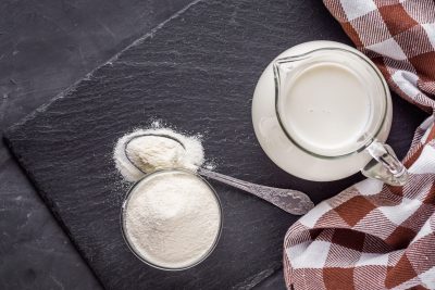 Un pichet de lait et une cuillère sur une table.