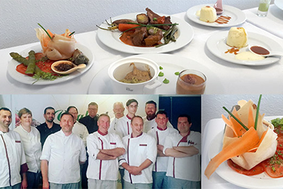 Un groupe de chefs pose devant des assiettes de nourriture.