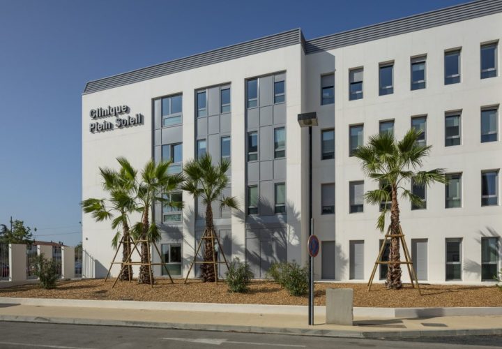 Un bâtiment blanc avec des palmiers devant.