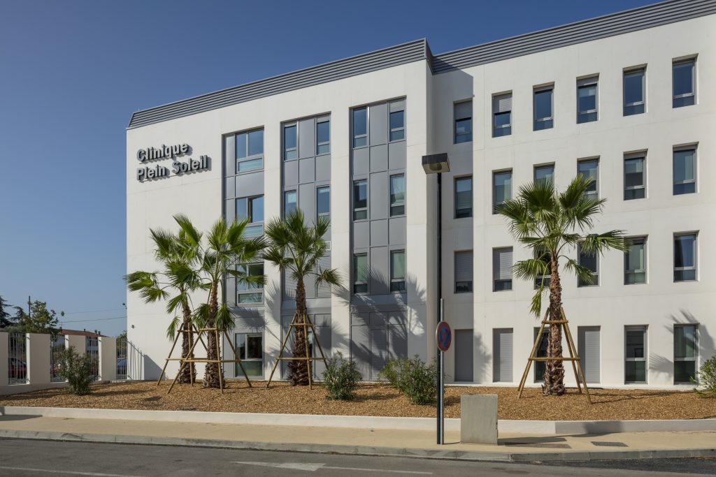 Un bâtiment blanc avec des palmiers devant.