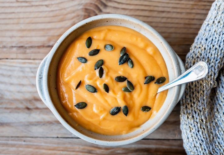 Un bol de soupe à la citrouille avec des graines de citrouille dessus.