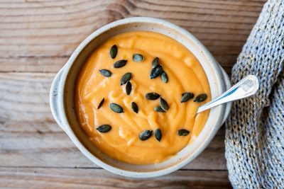 Un bol de soupe à la citrouille avec des graines de citrouille dessus.