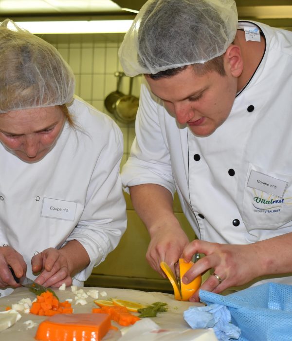 Deux chefs préparant des plats dans une cuisine.