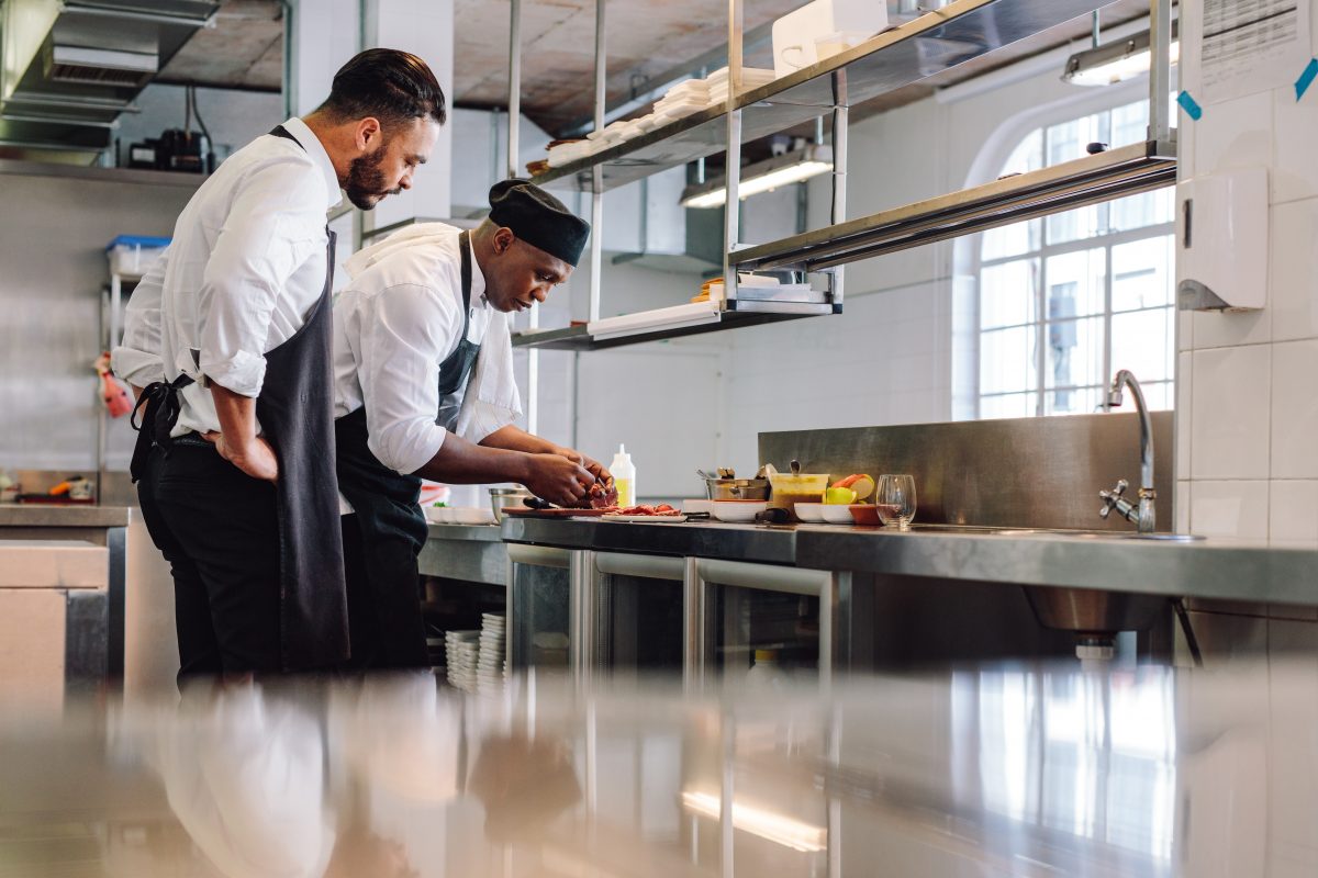 Deux chefs préparant des plats dans une cuisine commerciale.