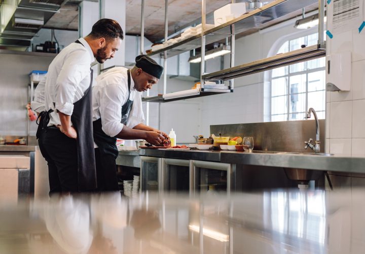 Deux chefs préparant des plats dans une cuisine commerciale.