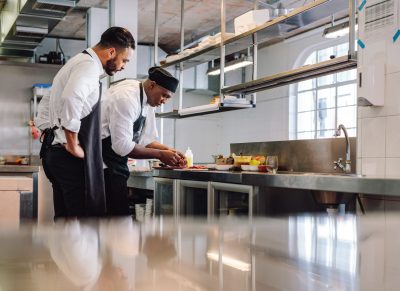 Deux chefs préparant des plats dans une cuisine commerciale.