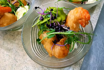 Crevettes et légumes dans des bols en verre sur un comptoir.