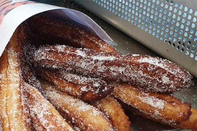 Les churros sont assis dans un panier avec du sucre en poudre.