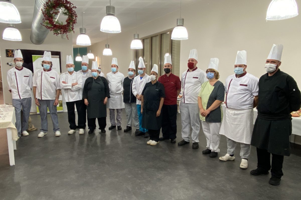 Un groupe de chefs posant pour une photo dans une cuisine.