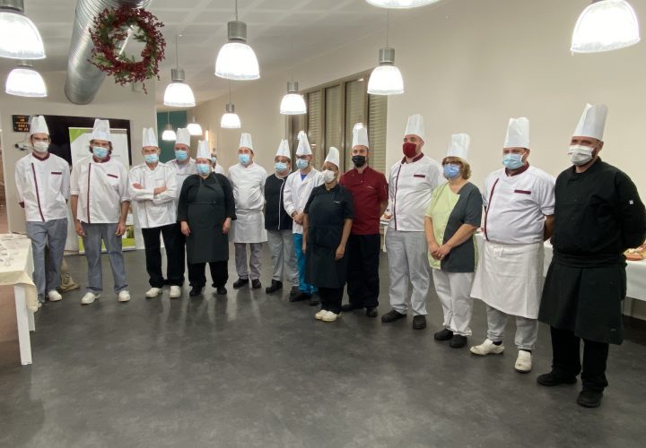 Un groupe de chefs posant pour une photo dans une cuisine.