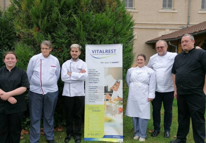 Un groupe de chefs posant devant une banderole.