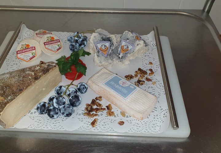 Un plateau de fromage, de fruits et de noix sur une table.