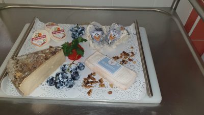 Un plateau de fromage, de fruits et de noix sur une table.