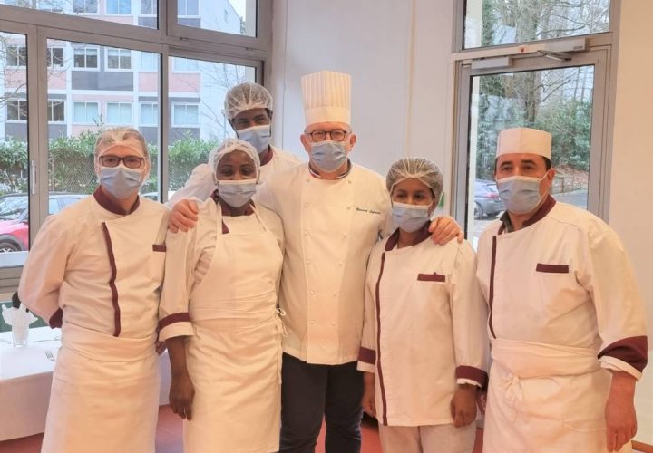 Un groupe de chefs portant des masques posant pour une photo.