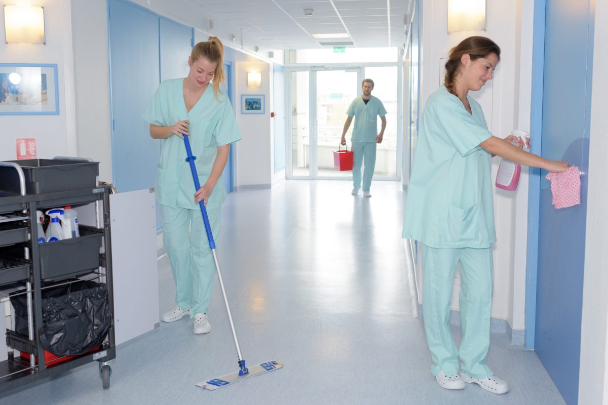 Deux femmes en blouse nettoyant un couloir dans un EHPAD.