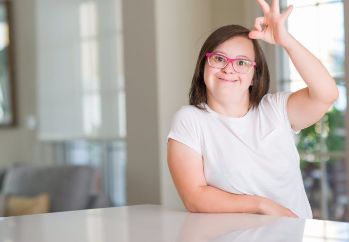 Une fille handicapée est assise à une table chez elle.