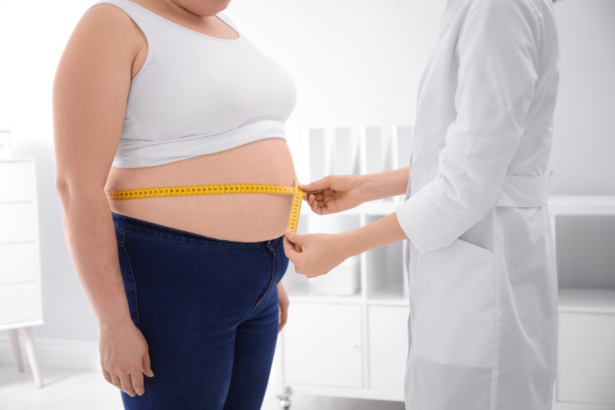 Une femme mesure son ventre avec un ruban à mesurer.