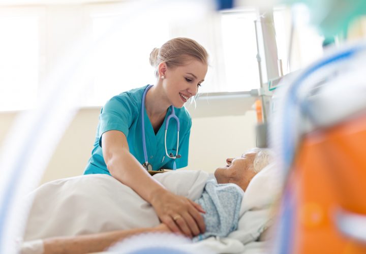 Une infirmière touche une femme âgée dans un lit d'hôpital.
