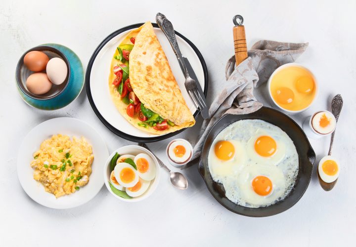 Omelette, œufs, crêpes et autres aliments pour le petit-déjeuner sur fond blanc.