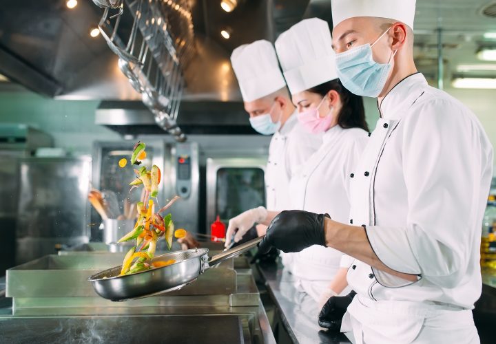 Chefs préparant des plats dans une cuisine commerciale.