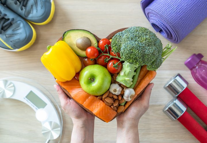 Une personne tient un bol de fruits et légumes en forme de cœur.