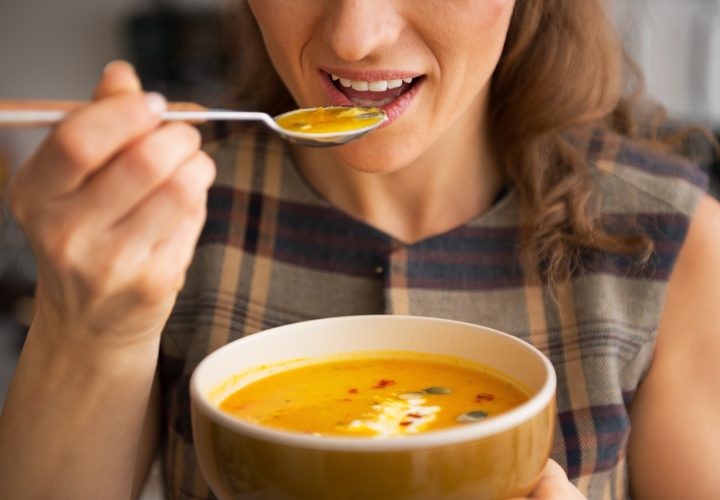 Une femme mange un bol de soupe avec une cuillère.