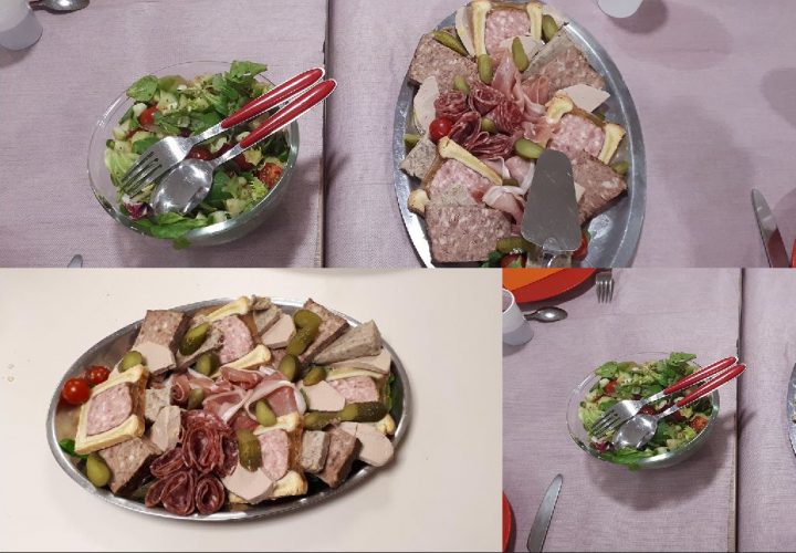 Une assiette de viande, de salade et de fourchettes sur une table.