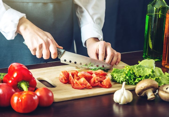 Un chef coupe des légumes sur une planche à découper.