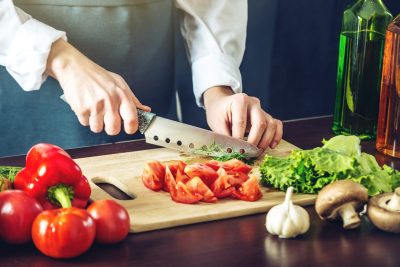 Un chef coupe des légumes sur une planche à découper.