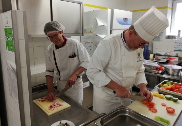 Deux chefs préparant des plats dans une cuisine.