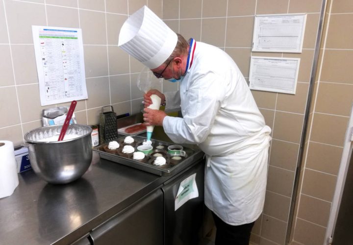Un chef prépare un gâteau dans une cuisine.
