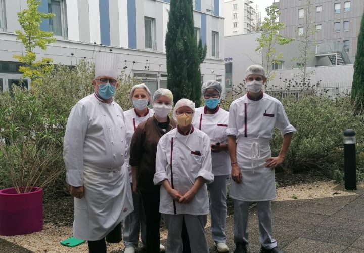 Un groupe de chefs portant des masques posant pour une photo.