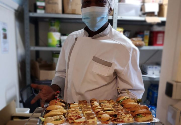 Un homme masqué tenant un plateau de sandwichs.