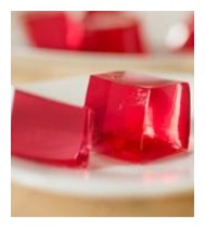 Cubes de gelée rouge sur une assiette blanche.