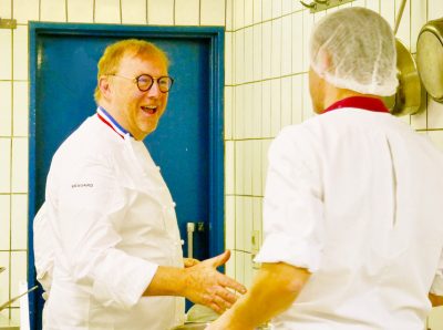 Deux chefs en uniforme blanc se parlent dans une cuisine.