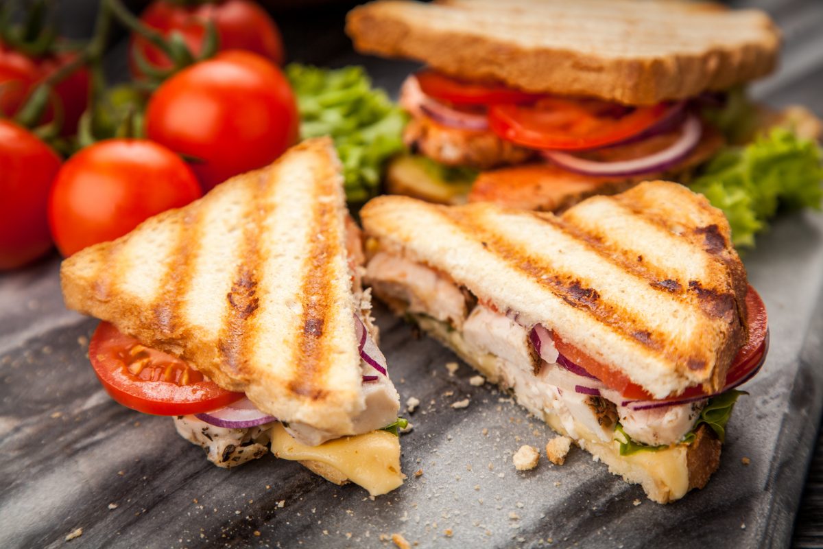 Un sandwich grillé avec des tomates et de la laitue sur une assiette.