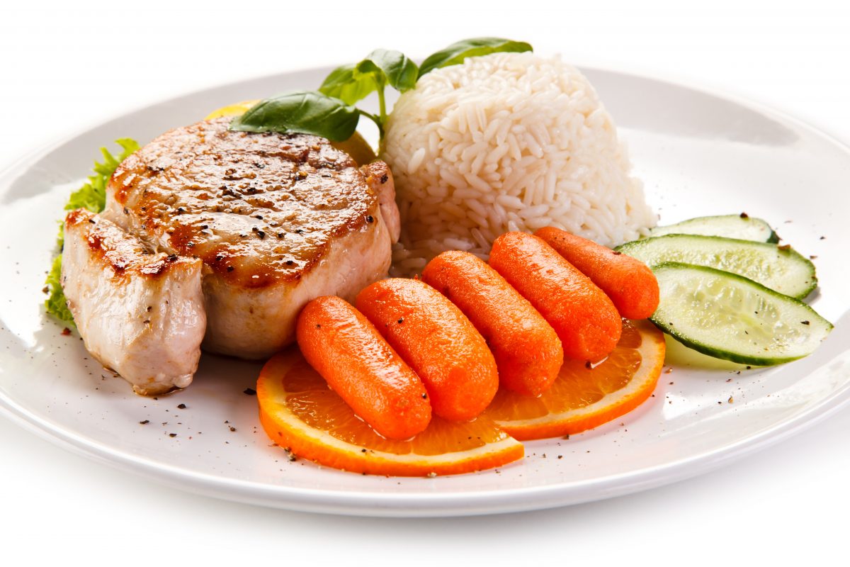 Une assiette blanche avec de la viande, des carottes et du riz.