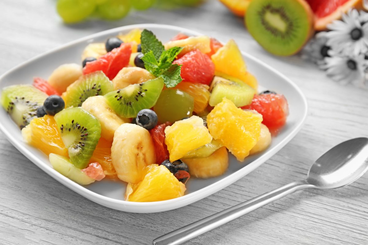 Un bol de salade de fruits sur une table en bois.