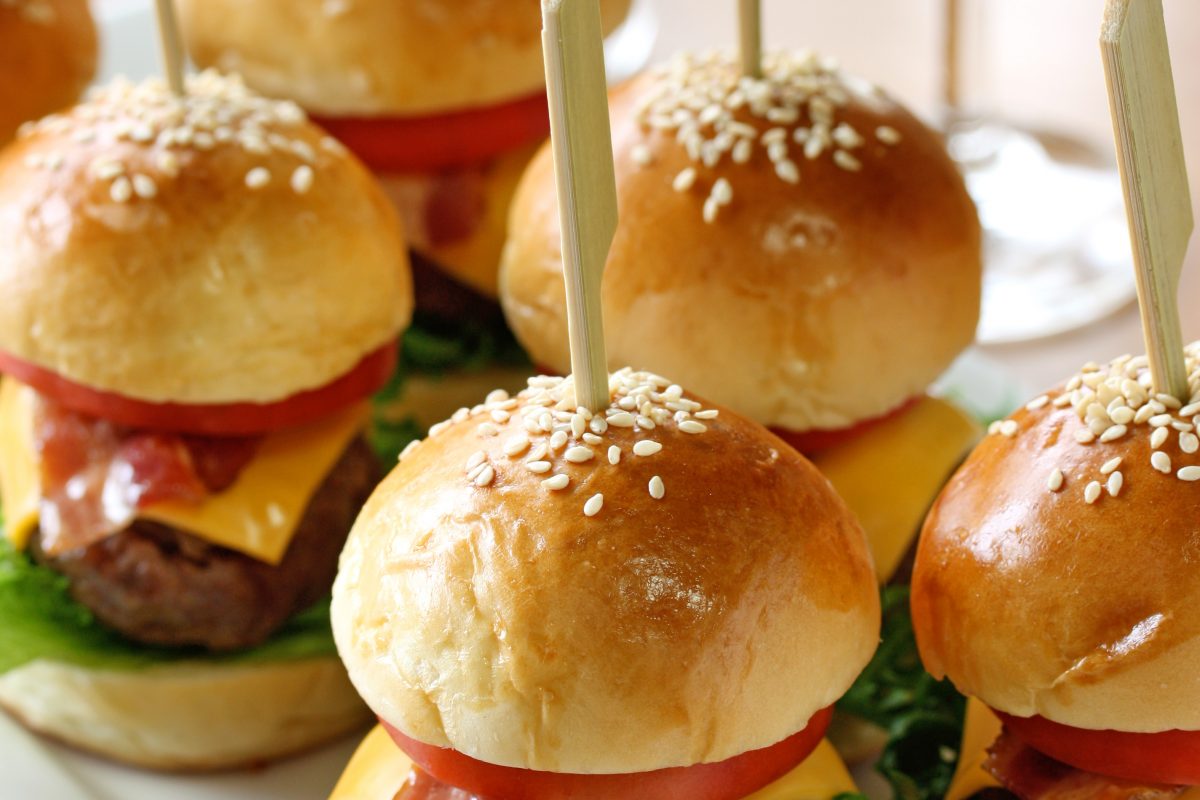 Curseurs de hamburger avec cure-dents sur une assiette blanche.