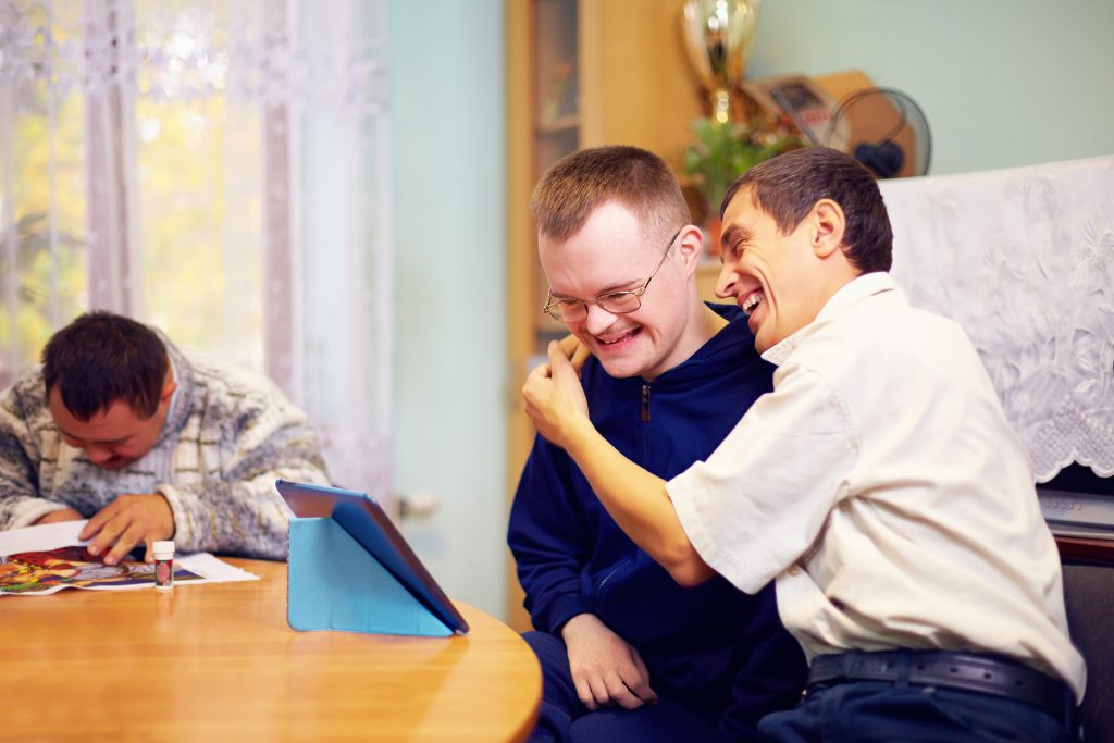 Un groupe d'hommes sont assis autour d'une table avec un iPad, discutant de restauration pour établissements accueillant des personnes en situation de handicap.
