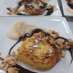 Une assiette de pain perdu avec sauce au chocolat et amandes.