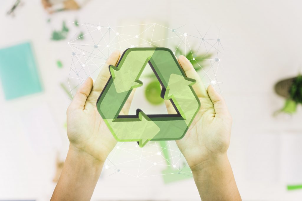 Les mains d'une femme tiennent un symbole de recyclage vert.