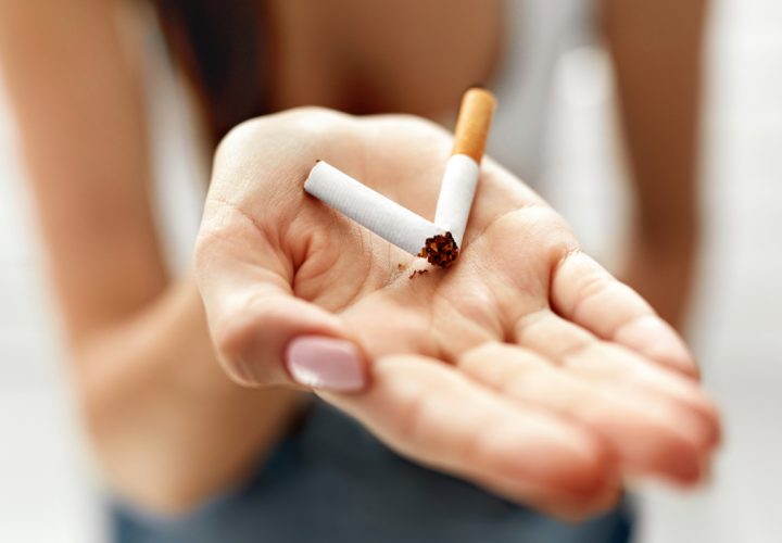 Une femme tenant une cigarette à la main.