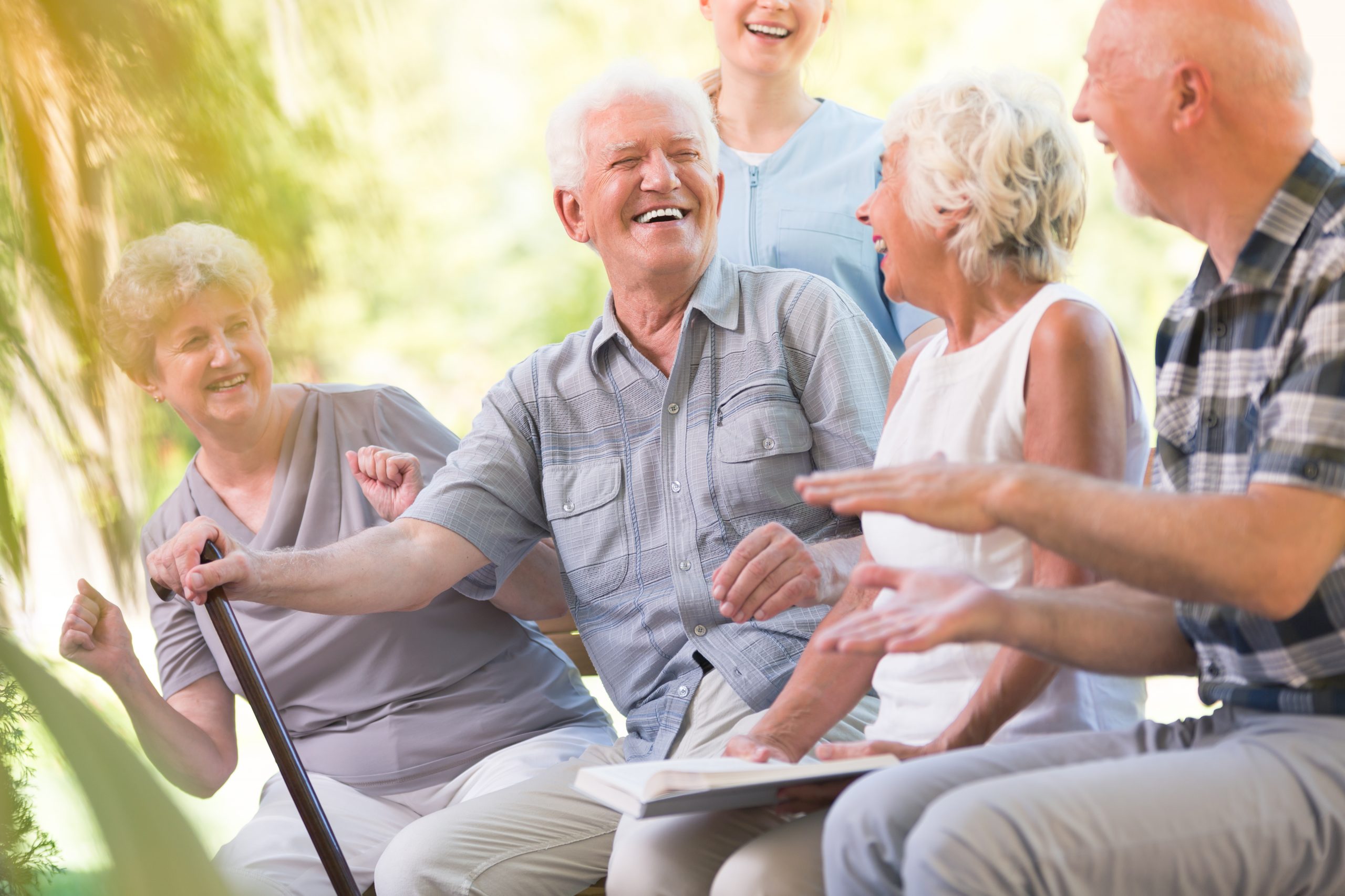 Un groupe de personnes âgées, contribuant au bien-être, assises sur un banc et riant.