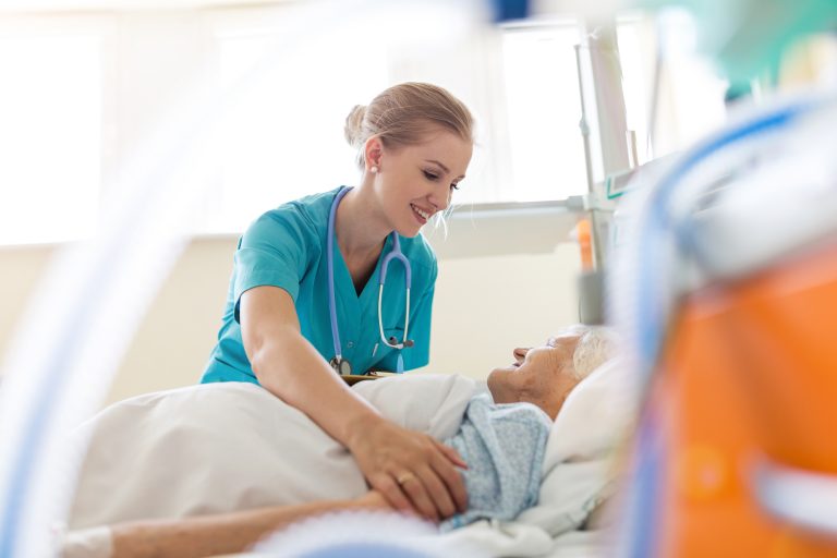 Une infirmière touche une femme âgée dans un lit d'hôpital.