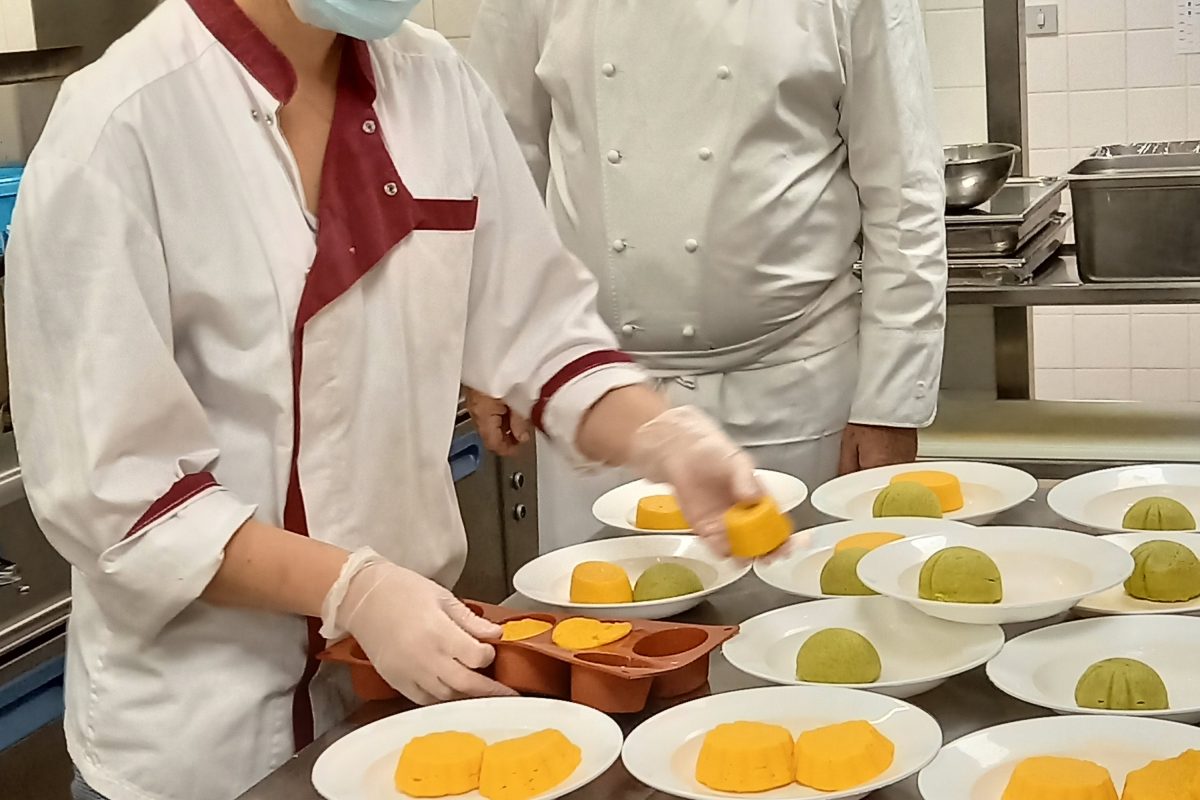 Deux chefs préparant des desserts dans une cuisine de restauration pour établissements accueillant des personnes en situation de handicap.