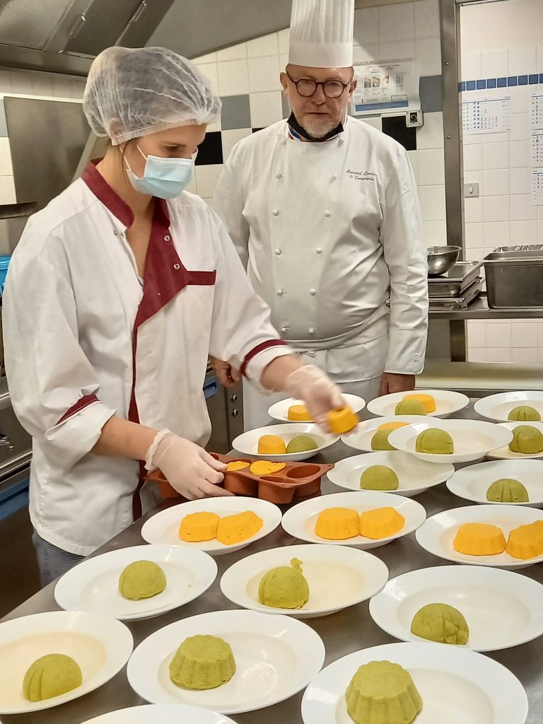 Deux chefs préparant des desserts dans une cuisine de restauration pour établissements accueillant des personnes en situation de handicap.