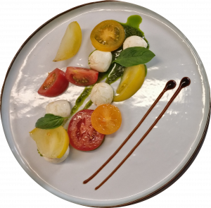 Une assiette avec des tomates, de la mozzarella et du basilic.