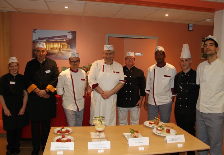 Un groupe de chefs posant devant une table avec de la nourriture dessus.